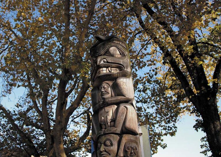 Totem pole reaches for the sky between trees